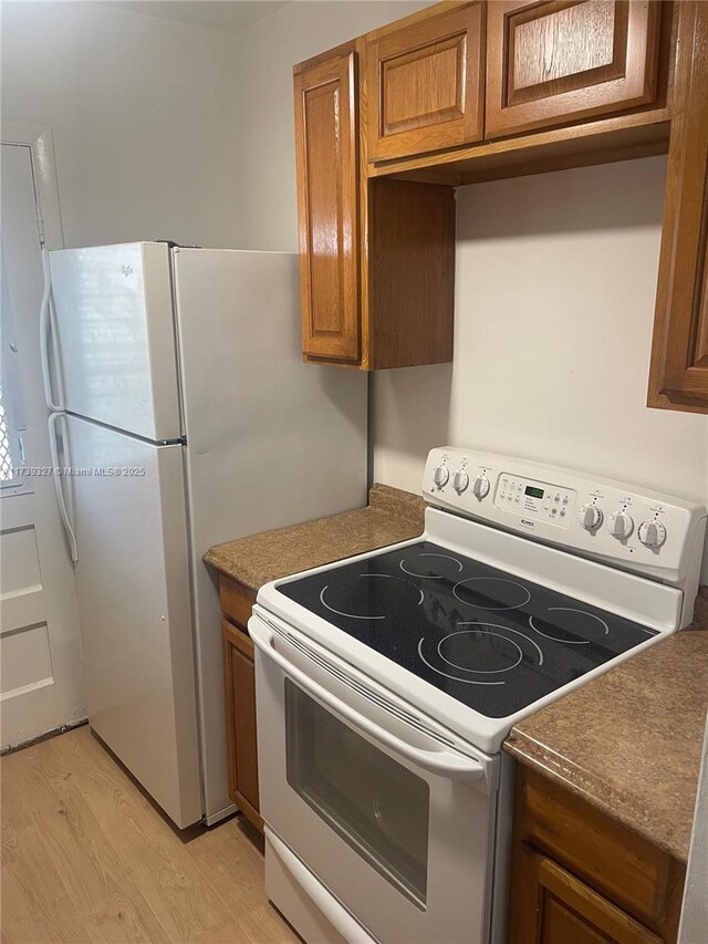 kitchen with white appliances and light hardwood / wood-style floors