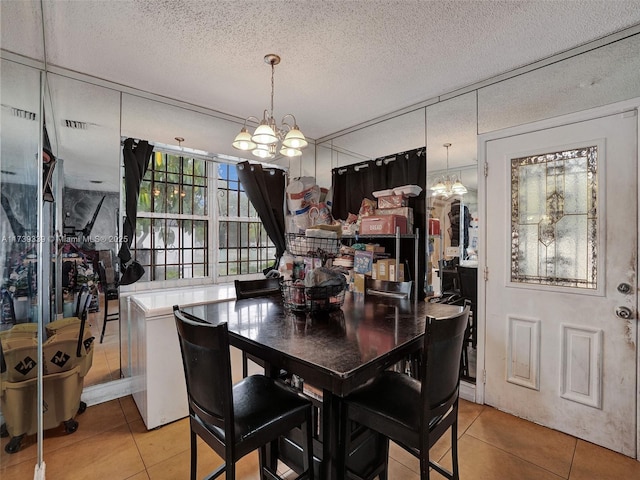 dining area featuring light tile patterned flooring, a notable chandelier, and a textured ceiling