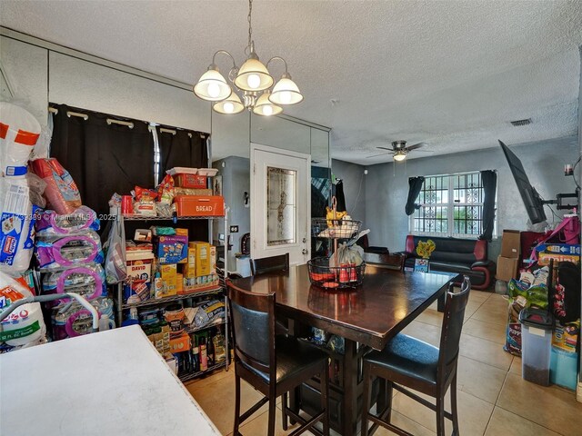 dining room featuring light tile patterned flooring, ceiling fan with notable chandelier, and a textured ceiling