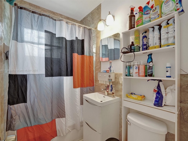 bathroom featuring a shower with curtain, vanity, toilet, and tile walls