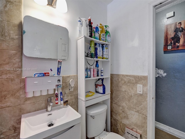 bathroom featuring vanity, tile walls, and toilet