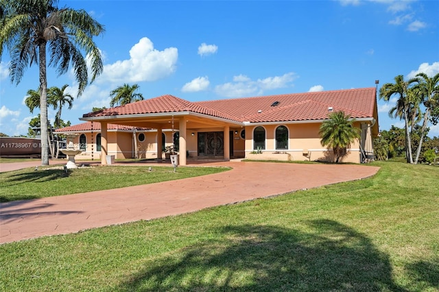 view of front facade with driveway, a tiled roof, a front yard, and stucco siding