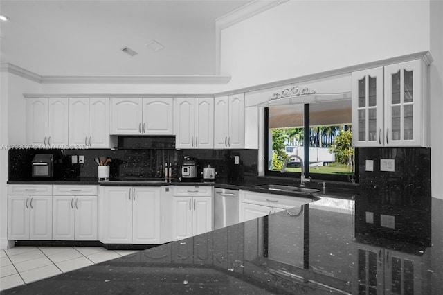 kitchen featuring light tile patterned floors, glass insert cabinets, white cabinetry, a sink, and dark stone countertops