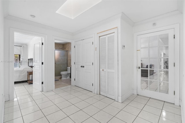 unfurnished bedroom with ornamental molding, a skylight, multiple closets, and light tile patterned floors