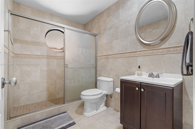 bathroom featuring tile walls, toilet, vanity, a shower stall, and tile patterned floors