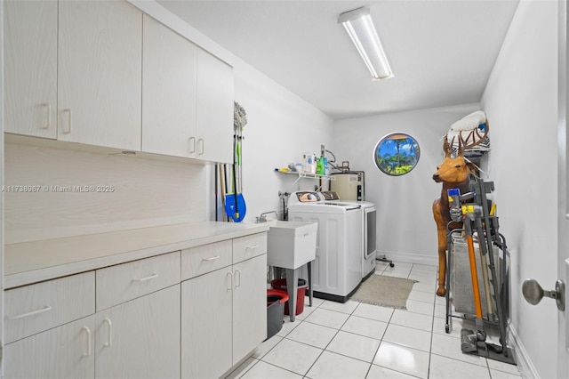 laundry room with cabinet space, baseboards, washing machine and clothes dryer, water heater, and light tile patterned flooring