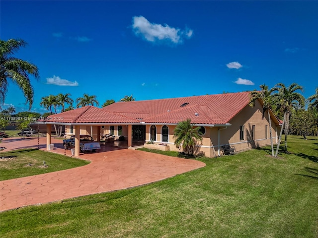 back of property with a tile roof, a lawn, and stucco siding