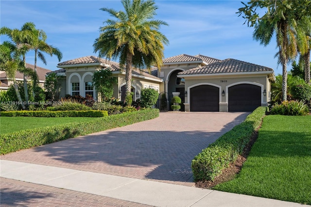 mediterranean / spanish-style home with a garage and a front lawn