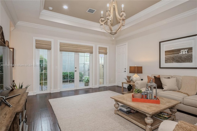 living room with crown molding, dark hardwood / wood-style floors, a raised ceiling, and a chandelier