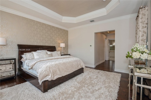 bedroom with dark wood-type flooring, a tray ceiling, and crown molding