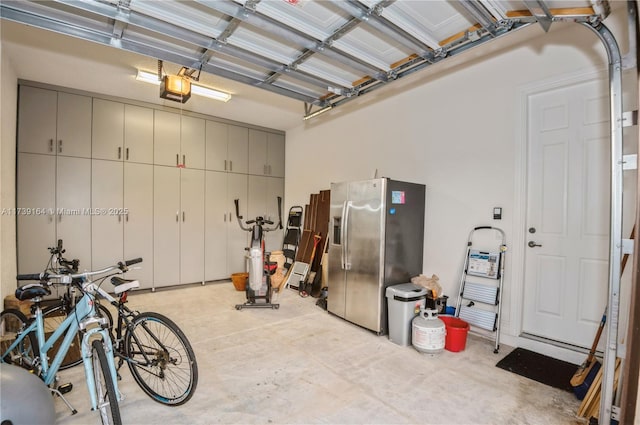 garage with a garage door opener and stainless steel fridge