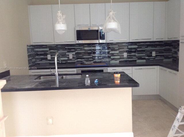 kitchen featuring decorative backsplash, sink, white cabinets, and decorative light fixtures