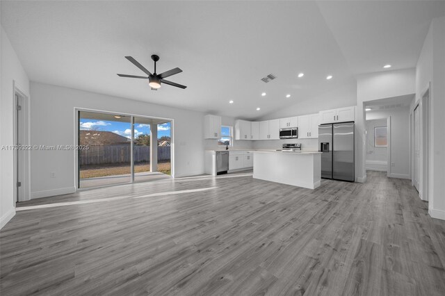 unfurnished living room with vaulted ceiling, light hardwood / wood-style floors, and ceiling fan