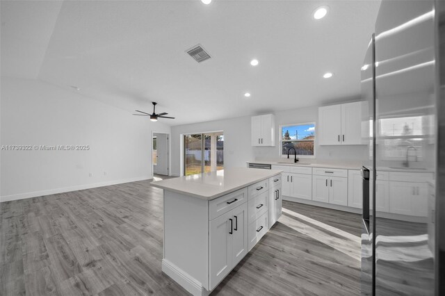 kitchen with sink, ceiling fan, a center island, white cabinets, and light wood-type flooring