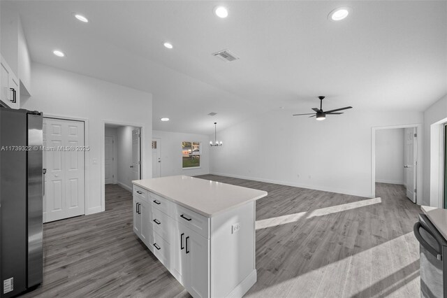 kitchen featuring a kitchen island, pendant lighting, stainless steel refrigerator, white cabinetry, and light hardwood / wood-style floors