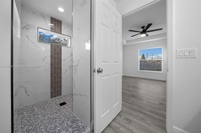 bathroom with hardwood / wood-style flooring, a healthy amount of sunlight, tiled shower, and ceiling fan