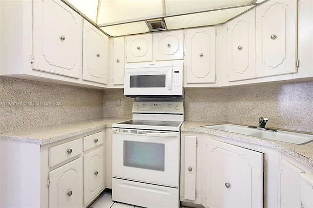 kitchen featuring white appliances, a sink, light countertops, and white cabinetry