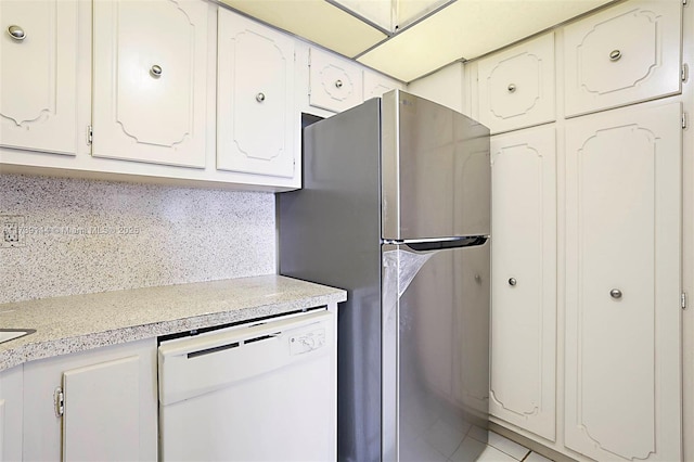 kitchen featuring white dishwasher, light countertops, freestanding refrigerator, and white cabinetry