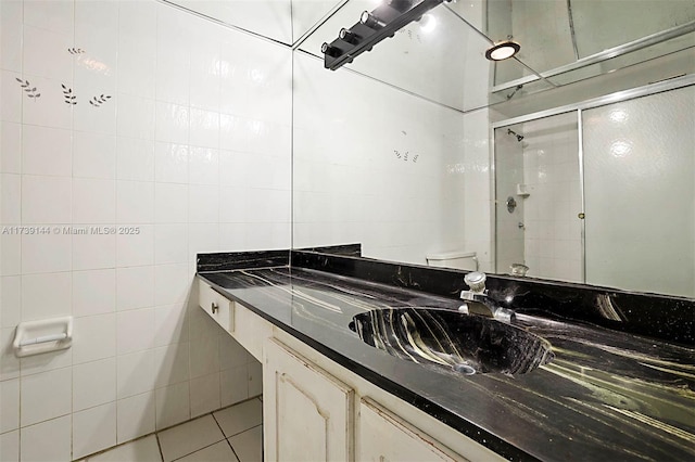 bathroom with a shower stall, tile patterned floors, vanity, tile walls, and toilet