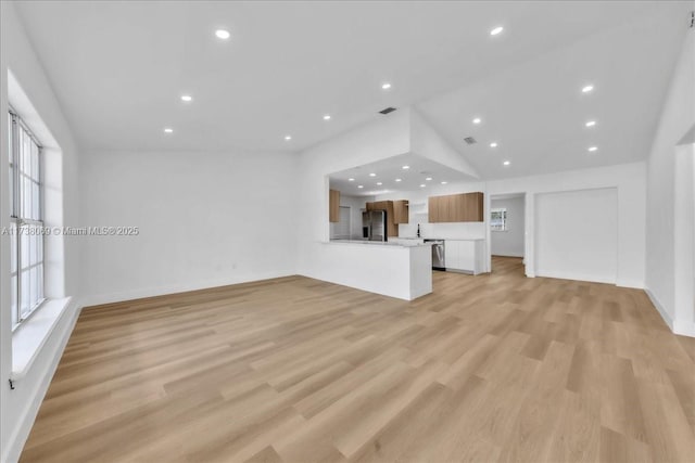 unfurnished living room with vaulted ceiling and light hardwood / wood-style flooring