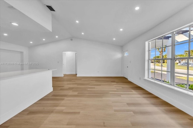 unfurnished living room with vaulted ceiling and light wood-type flooring