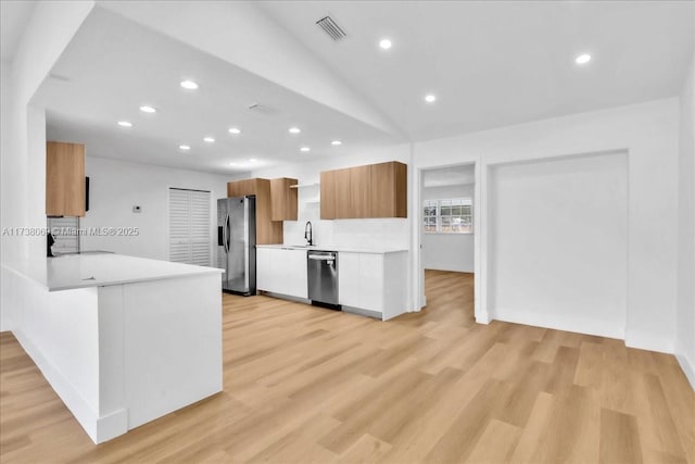 kitchen with sink, stainless steel appliances, light hardwood / wood-style floors, and white cabinets