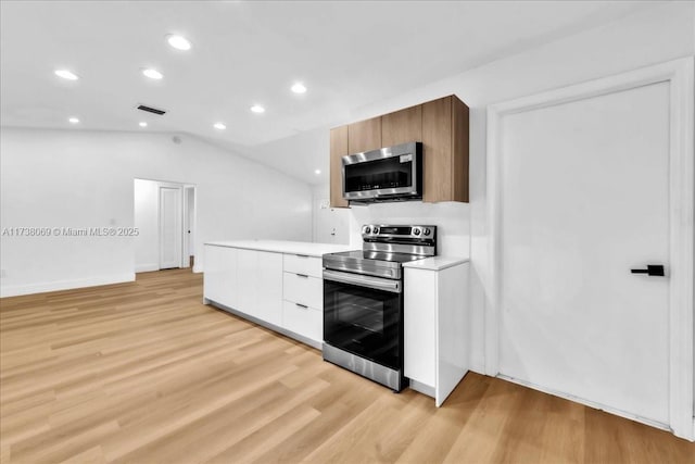 kitchen with vaulted ceiling, stainless steel appliances, light hardwood / wood-style floors, and white cabinets