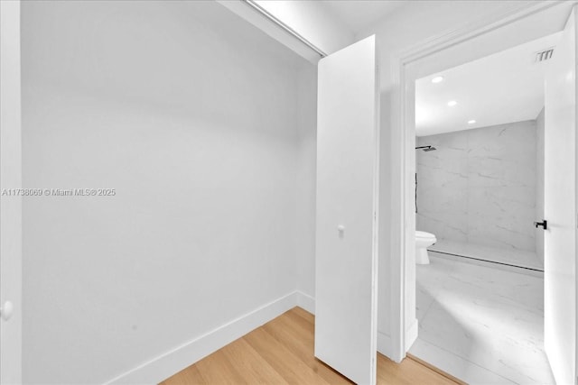 bathroom featuring hardwood / wood-style flooring, toilet, and a tile shower