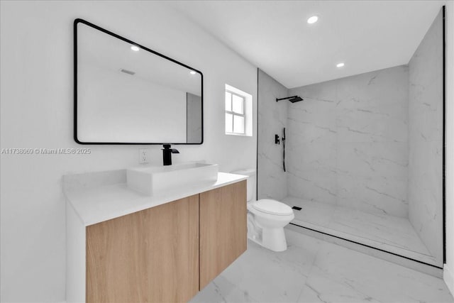 bathroom with vanity, toilet, and a tile shower