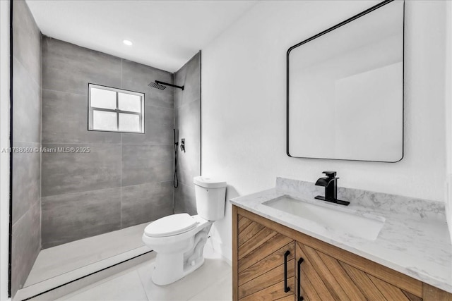 bathroom with tile patterned flooring, vanity, tiled shower, and toilet