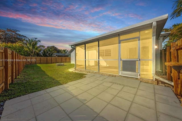 patio terrace at dusk with a lawn and a sunroom