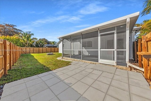 rear view of house featuring a lawn, a sunroom, and a patio