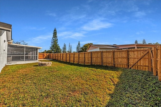 view of yard featuring a fire pit and a sunroom