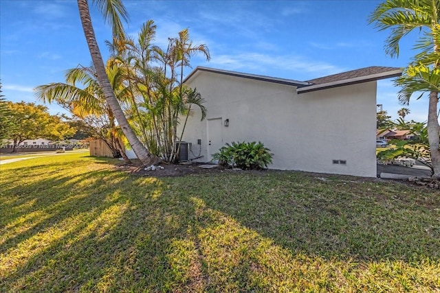 view of side of home with central AC unit and a yard