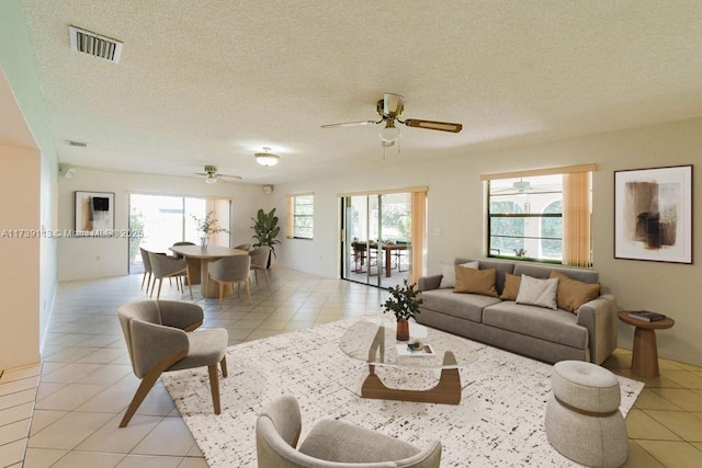 living room with light tile patterned flooring, a textured ceiling, and a wealth of natural light