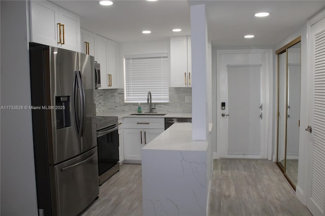 kitchen with sink, light hardwood / wood-style flooring, white cabinetry, stainless steel appliances, and light stone counters