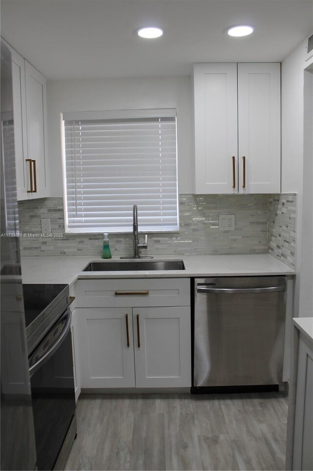 kitchen with sink, white cabinetry, stainless steel dishwasher, electric stove, and light hardwood / wood-style floors