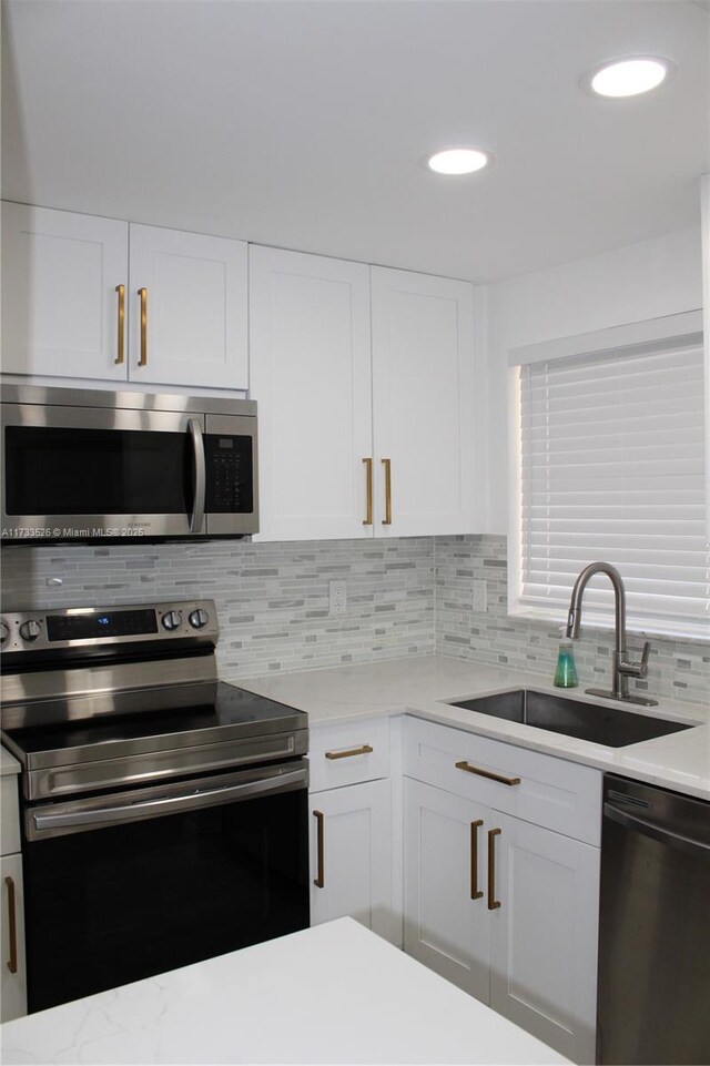 kitchen featuring tasteful backsplash, sink, white cabinets, and appliances with stainless steel finishes