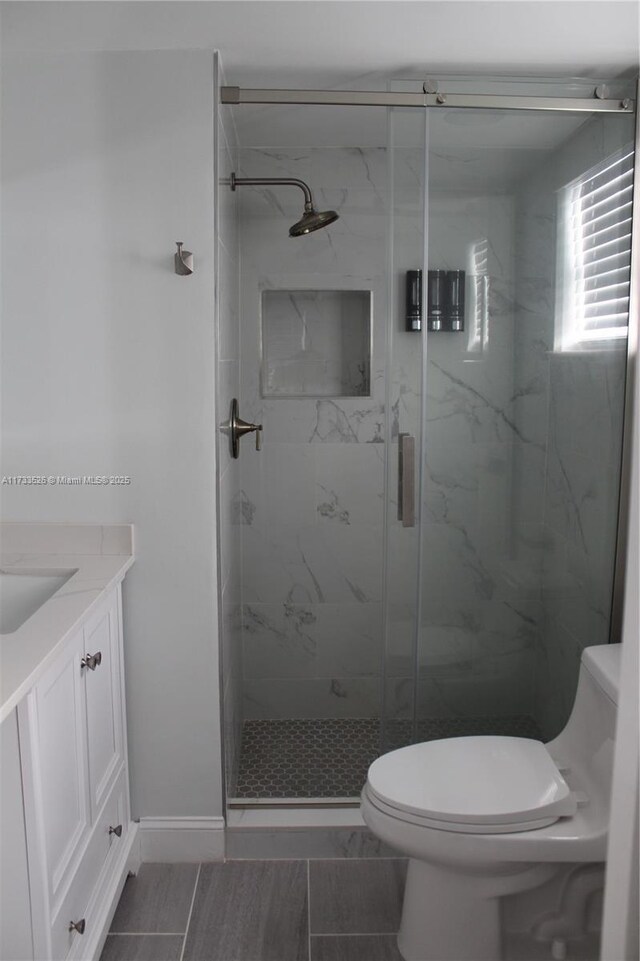 bathroom featuring vanity, a shower with shower door, and toilet