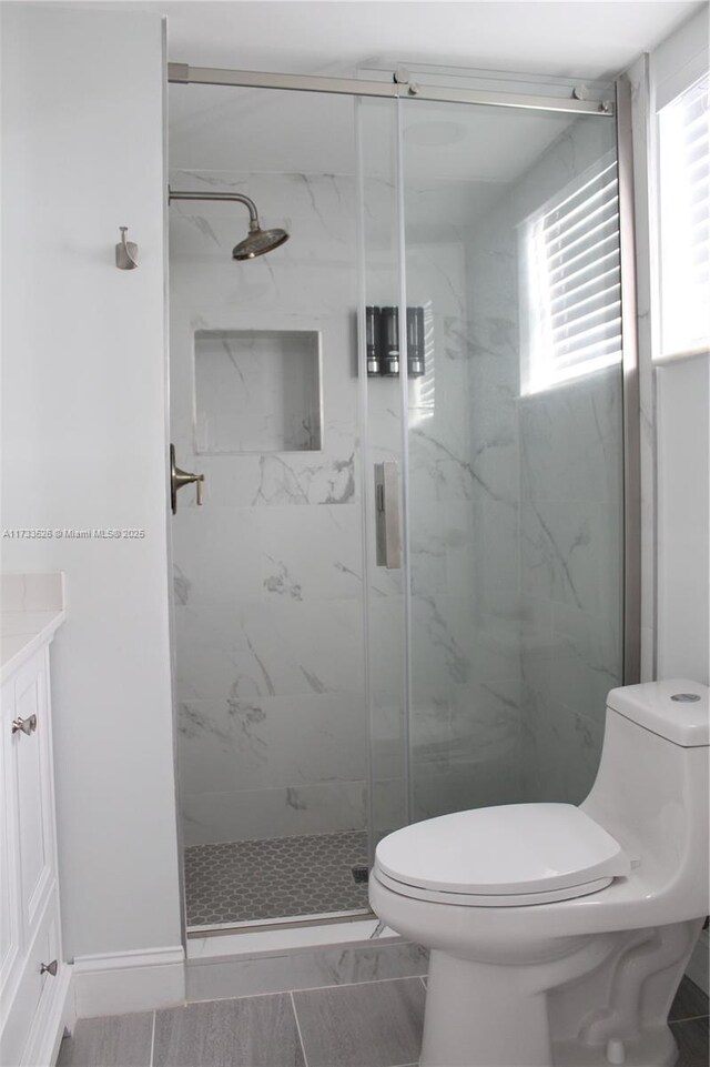 bathroom featuring vanity, an enclosed shower, and toilet