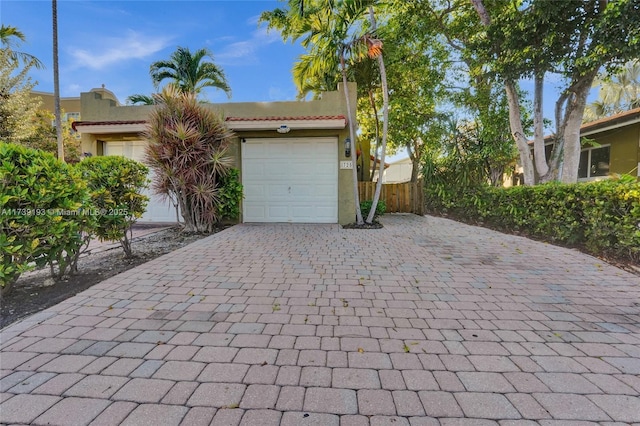 garage featuring decorative driveway and fence