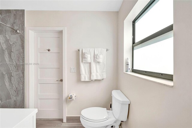 bathroom with hardwood / wood-style flooring, toilet, and walk in shower