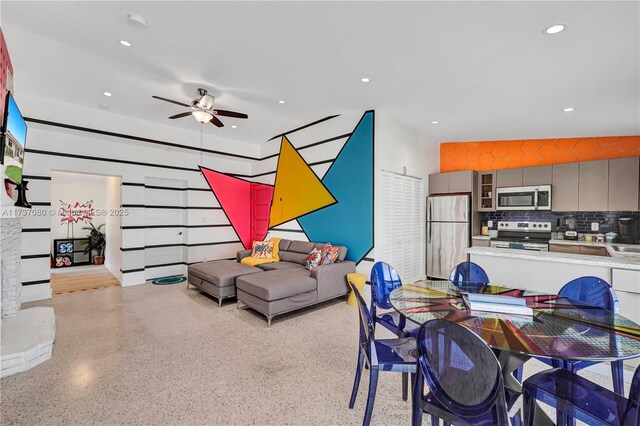 living room featuring a stone fireplace, a towering ceiling, and ceiling fan