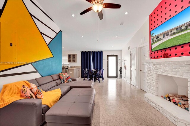 living room with a brick fireplace and ceiling fan