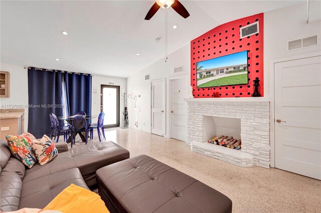 living room featuring lofted ceiling, a stone fireplace, and ceiling fan