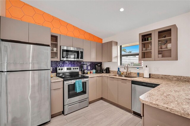 kitchen featuring sink, gray cabinets, appliances with stainless steel finishes, tasteful backsplash, and light hardwood / wood-style floors