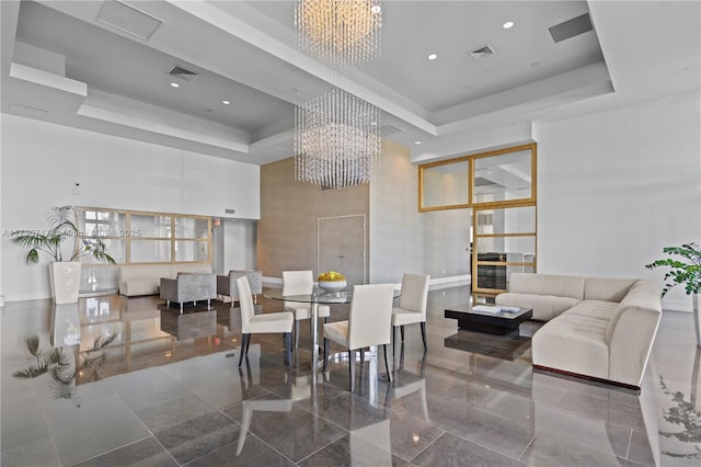 dining space with a high ceiling, a notable chandelier, and a tray ceiling