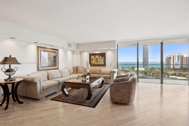 living room with a water view, a wall of windows, and light hardwood / wood-style floors