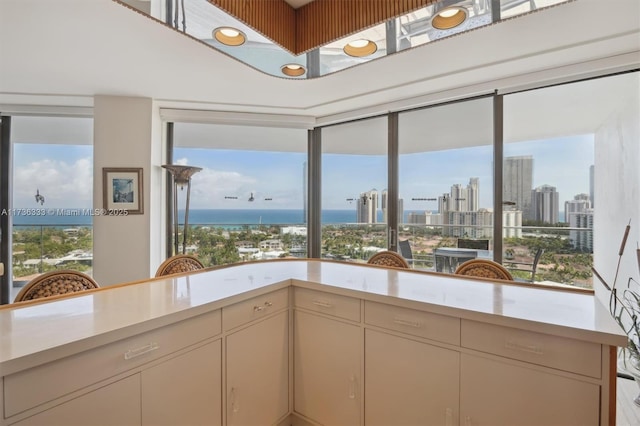 kitchen featuring a water view, a wealth of natural light, kitchen peninsula, and cream cabinetry