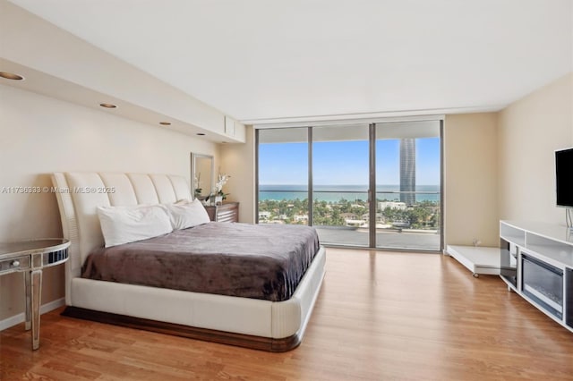 bedroom featuring expansive windows, access to exterior, and light wood-type flooring